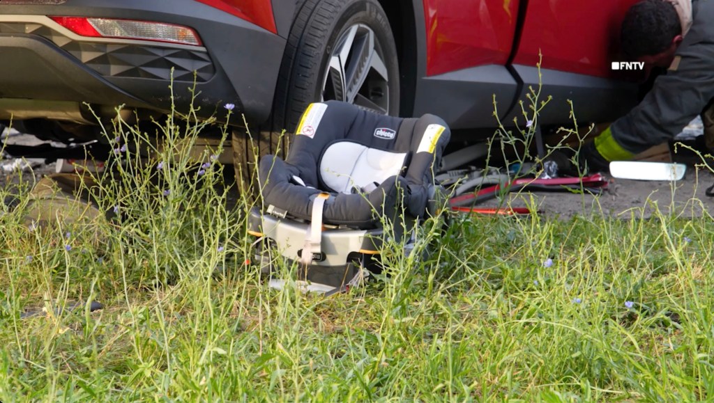 Infant car seat near damaged car at accident scene.