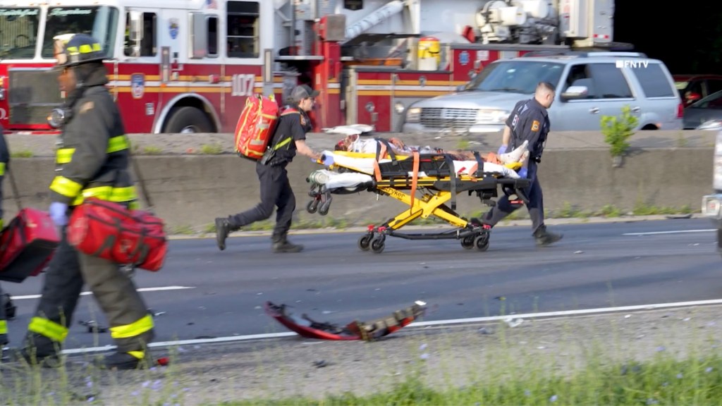 First responders wheeling an injured person on a stretcher from a multi-vehicle accident.