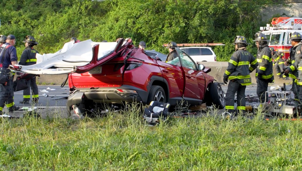 Aftermath of a serious multi-vehicle crash with overturned cars and firefighters on the scene.