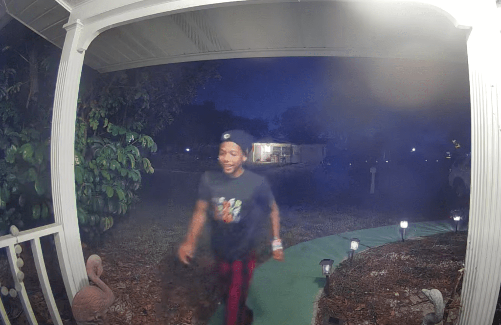 Nighttime security camera footage of a person walking on a pathway.