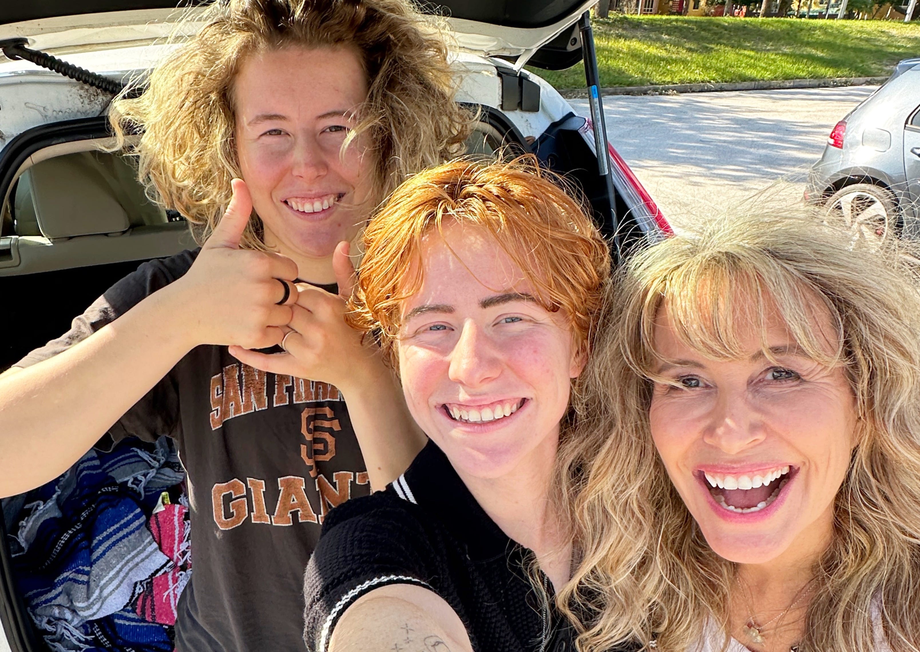 The author with her two kids smiling at the camera while packing the trunk of a car.