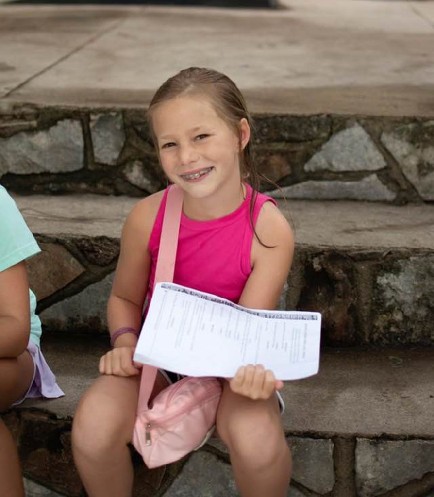 Girl at summer camp holding paperwork.