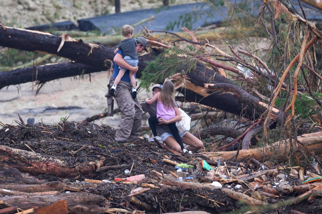 Family climbs over flood debris.