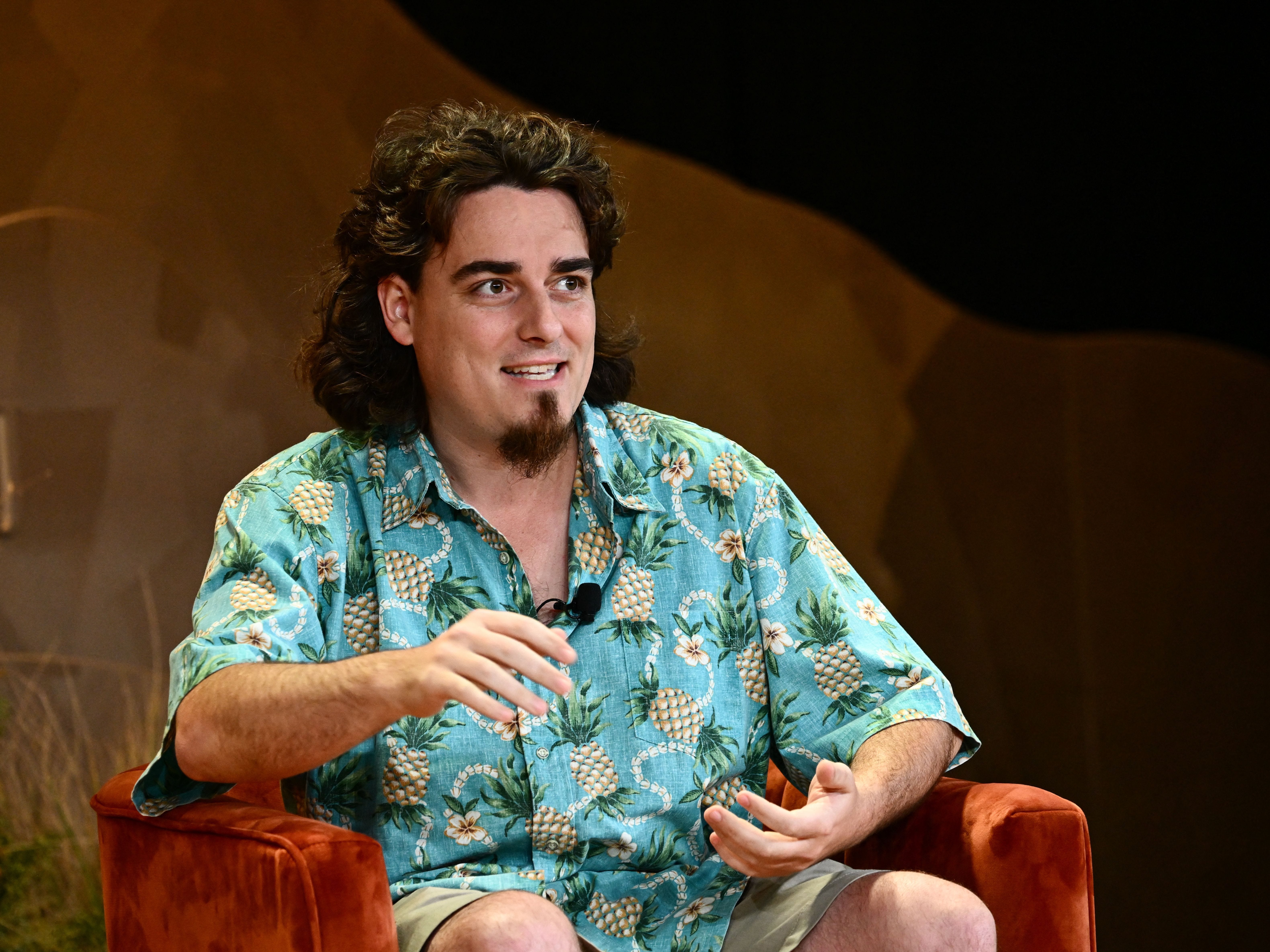 Palmer Luckey, wearing a Hawaiian shirt with a pineapple print, speaking at a conference.
