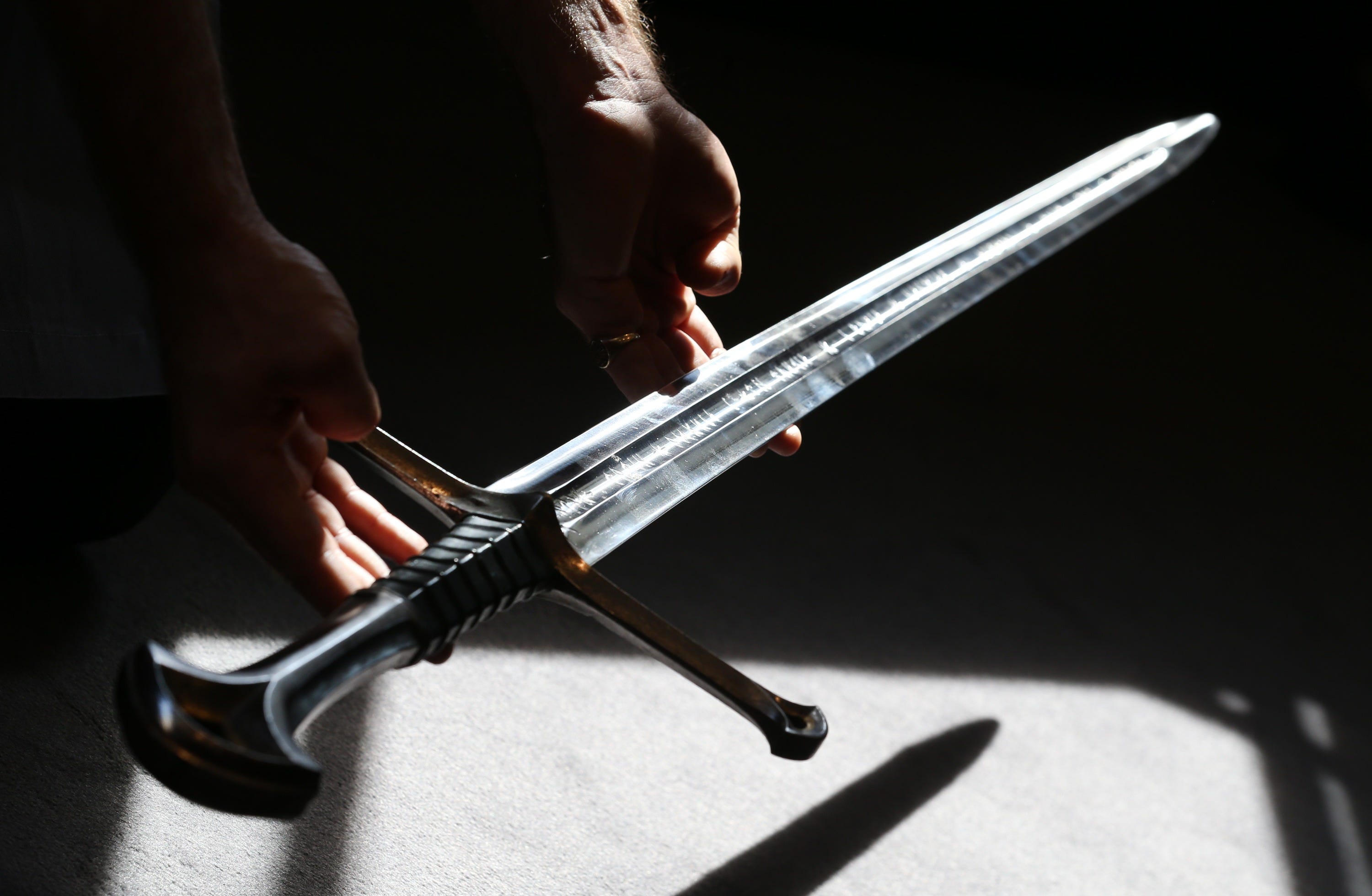 Two hands present a sword with an enscription