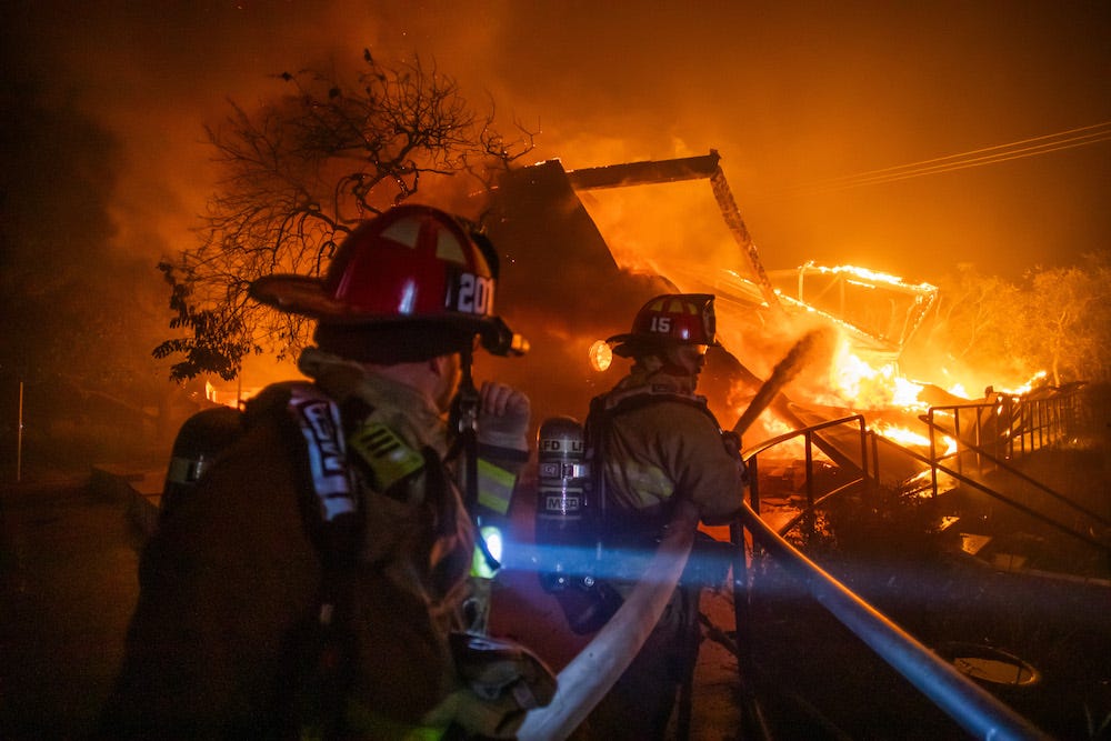 Firefighters fight the flames from the Palisades Fire burning the Theatre Palisades during a powerful windstorm on January 8, 2025 in the Pacific Palisades neighborhood of Los Angeles, California. The fast-moving wildfire is threatening homes in the coastal neighborhood amid intense Santa Ana Winds and dry conditions in Southern California.