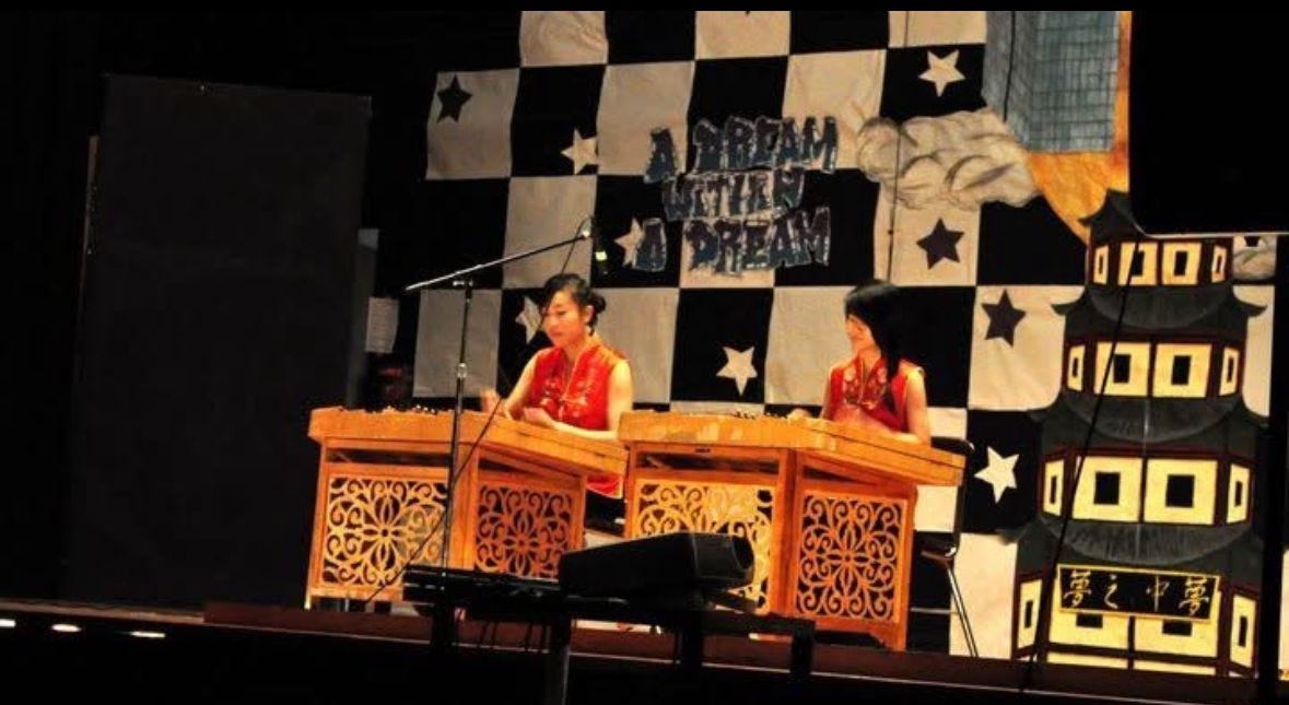 High school student playing yangqin, a Chinese stringed instrument, onstage.