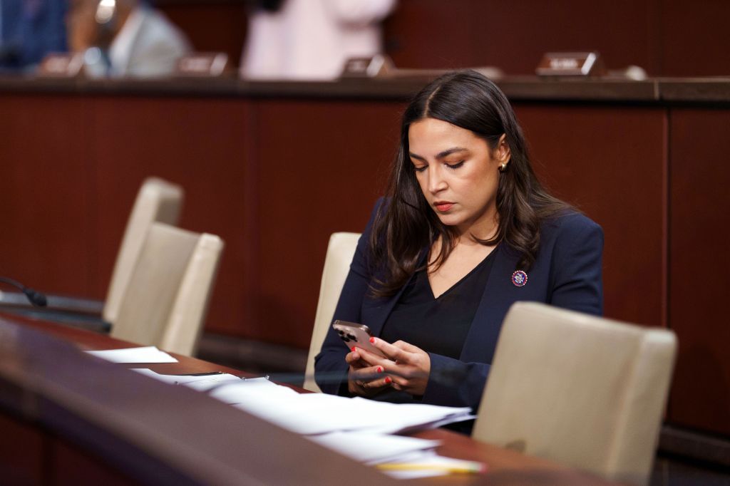 Alexandria Ocasio-Cortez on her phone at a House Oversight Committee hearing.