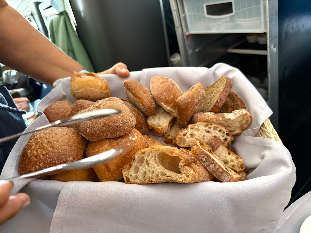 Bread basket on a plane, someone holding tongs next to it