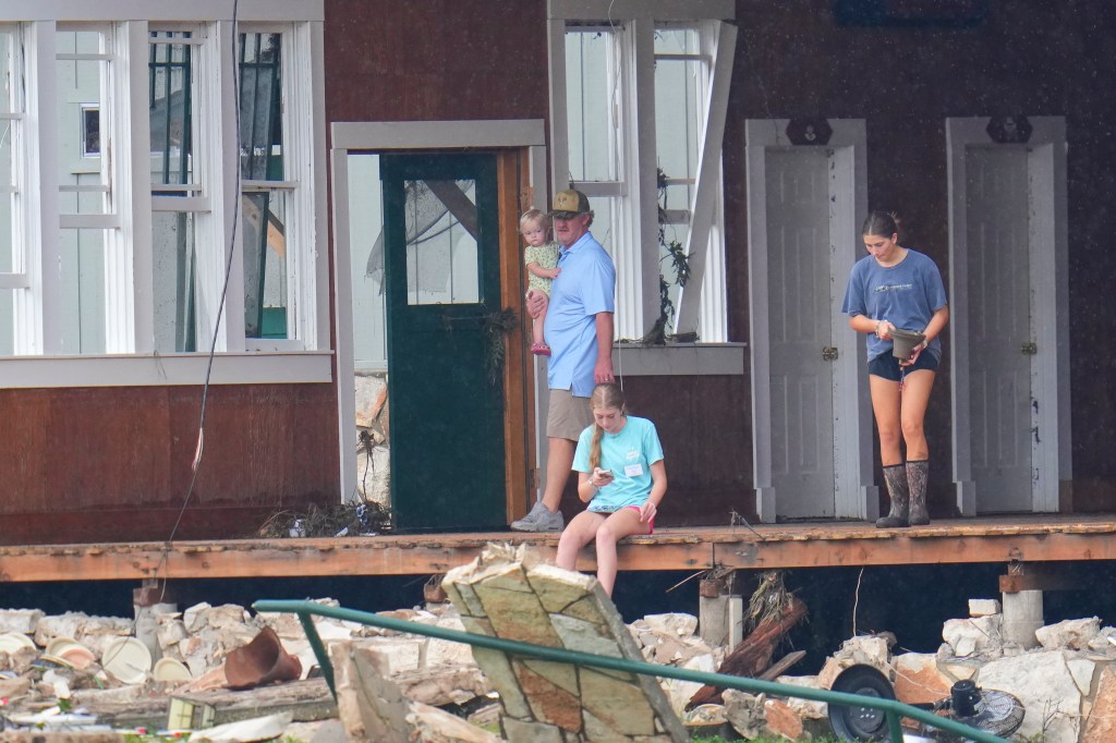 A family surveys the damage to their flood-ravaged home.