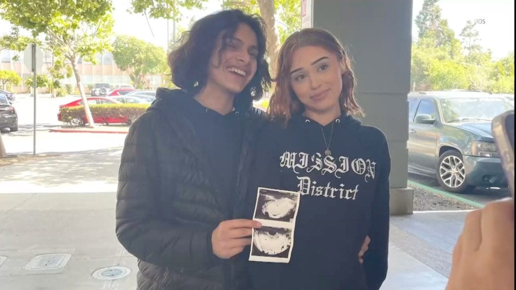 Photo of a young couple holding ultrasound images.