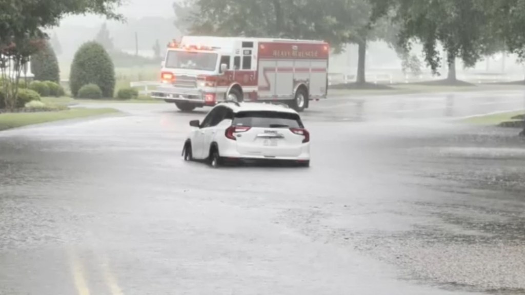 Flooded road with a car and firetruck.