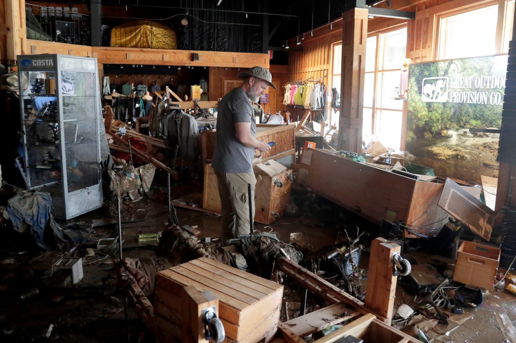 A man surveys flood damage in a store.