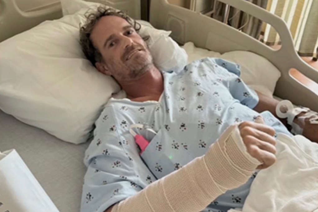 Man in hospital bed with arm in cast.