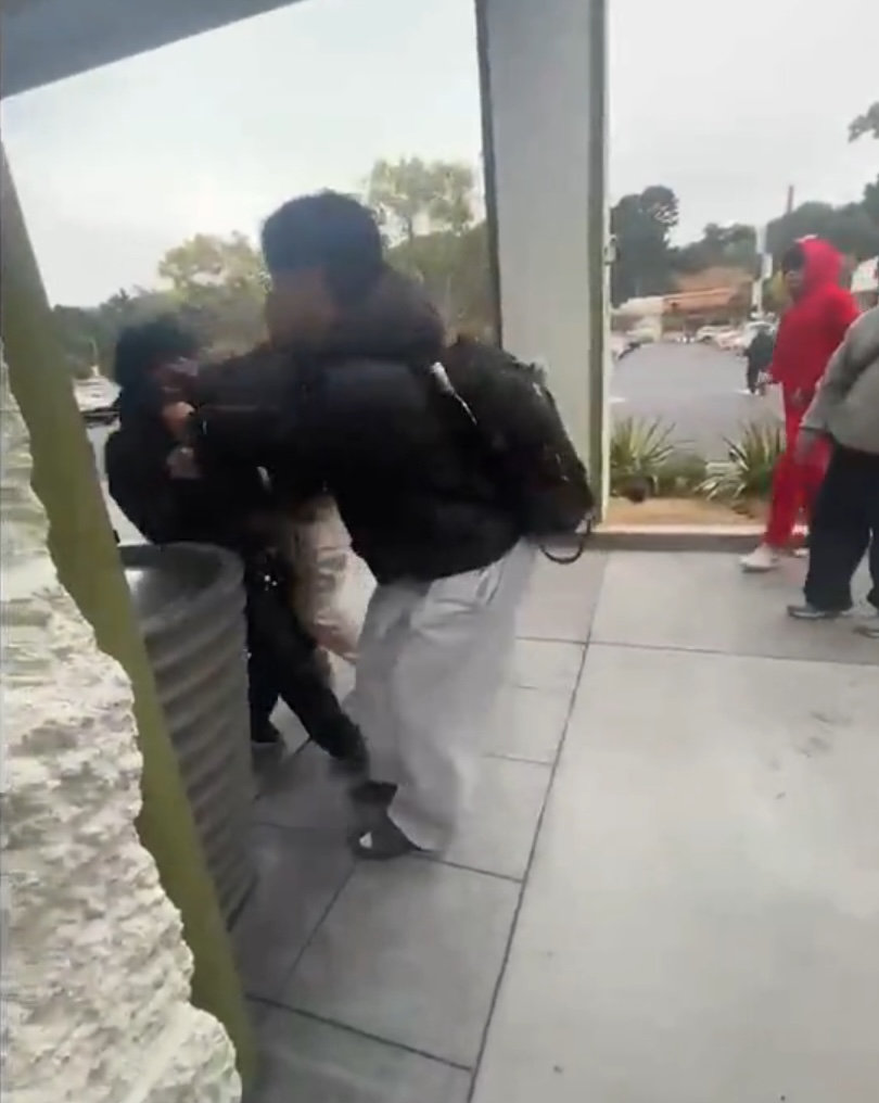 Two people fighting outside a building.