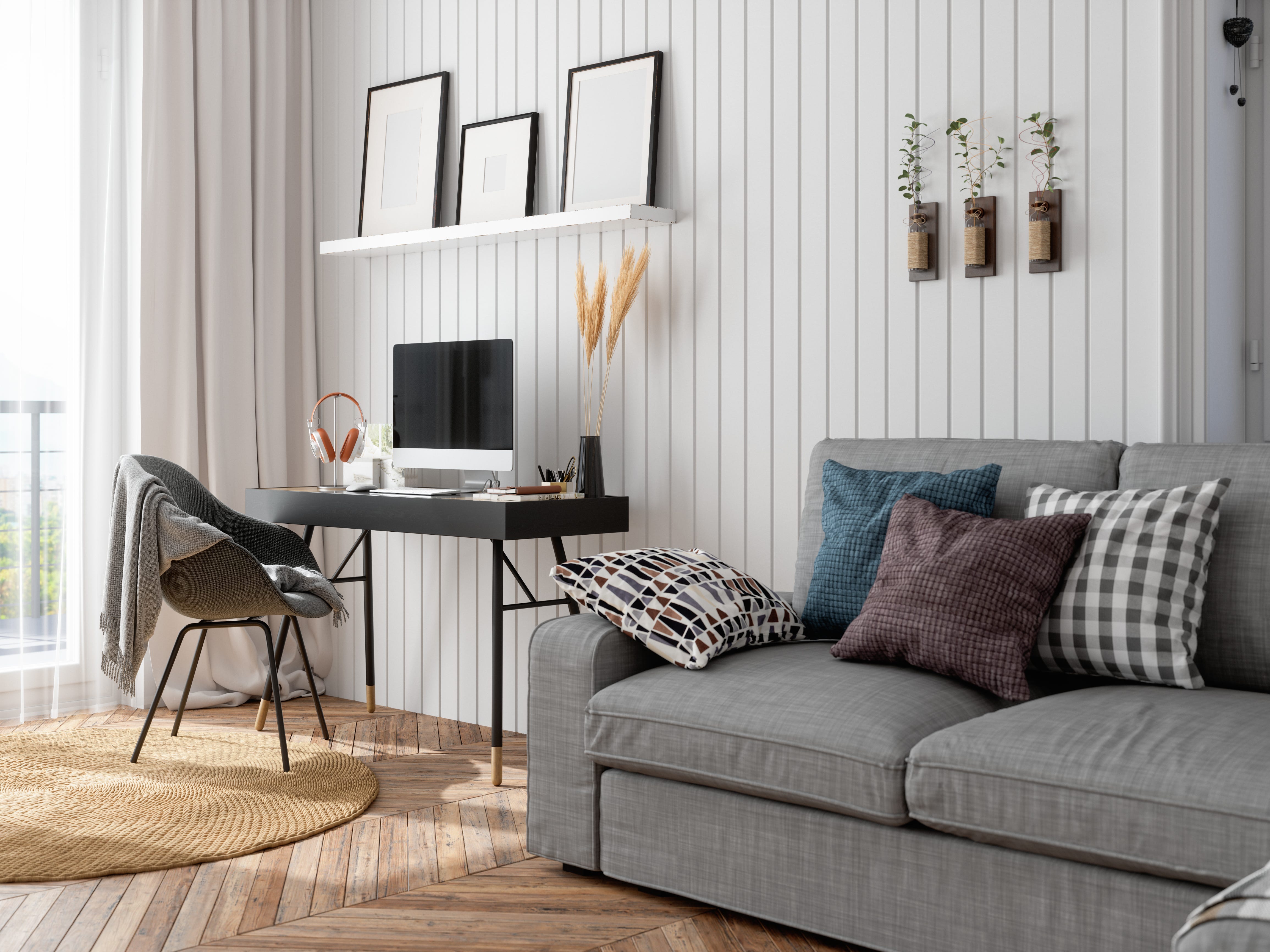 Living room with a gray shiplap wall, a desk, and a gray couch with patterned pillows.