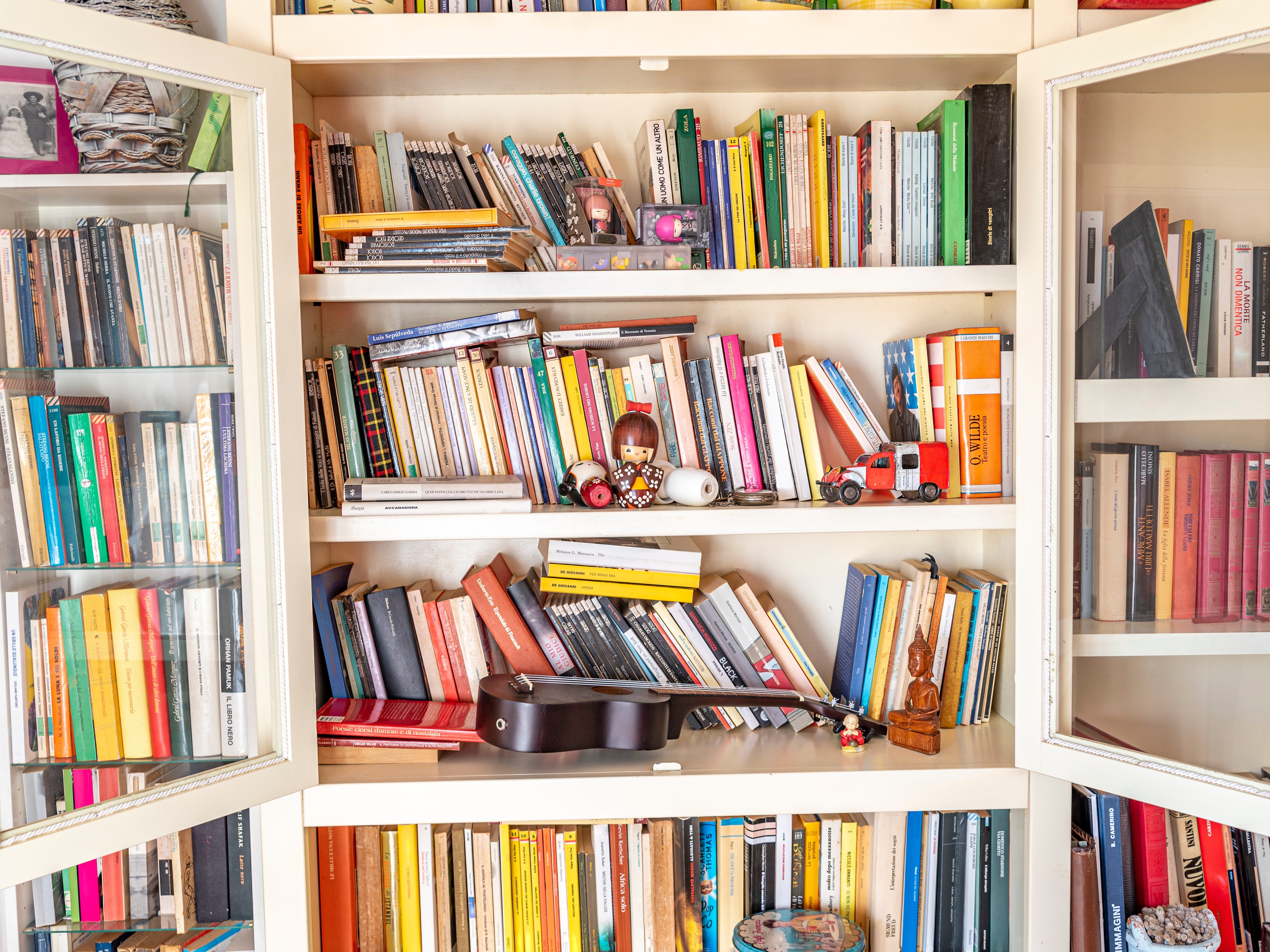 A cluttered bookshelf with books, children's toys, and trinkets.