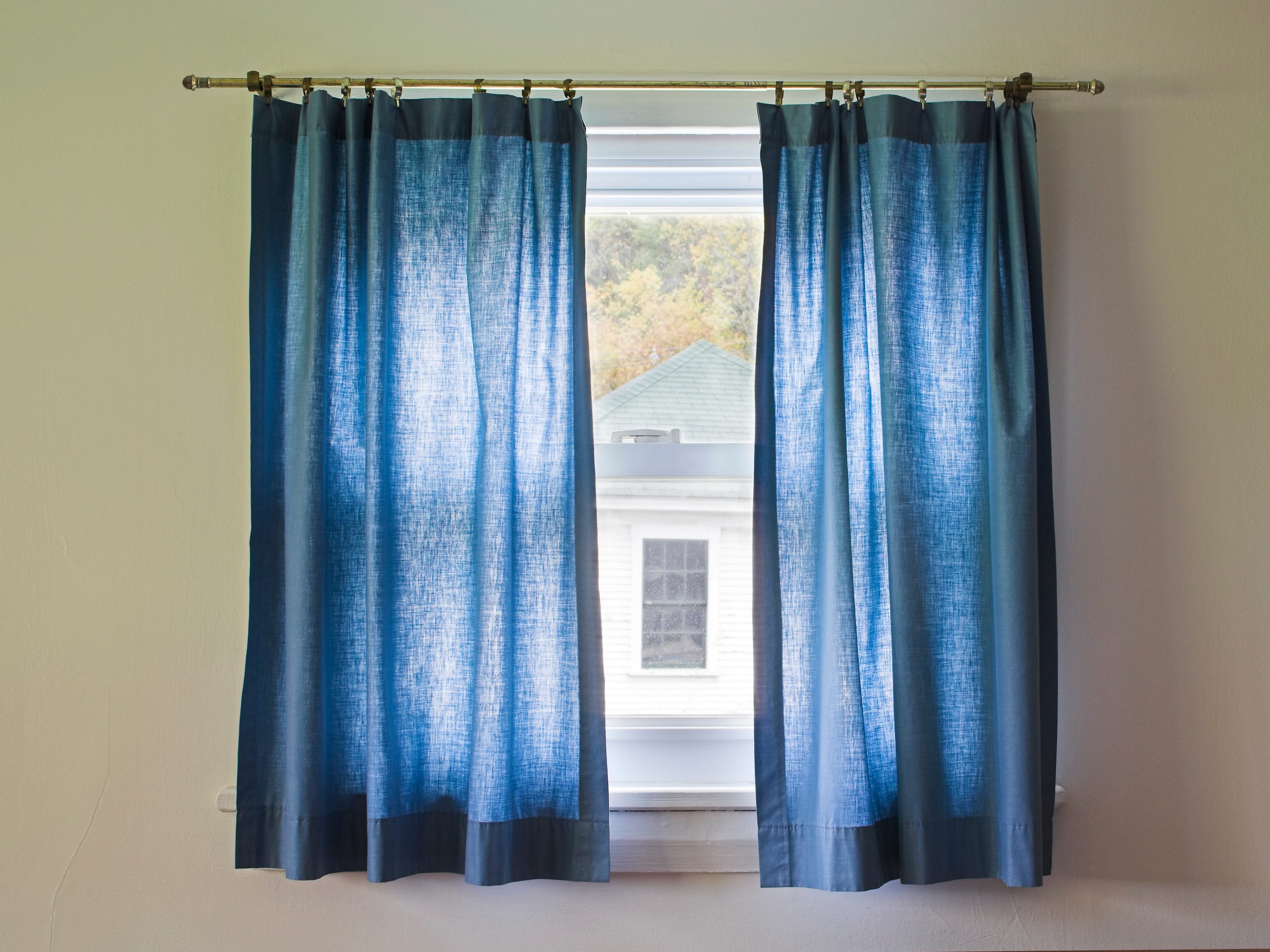 Short, thin, blue curtains on a window.