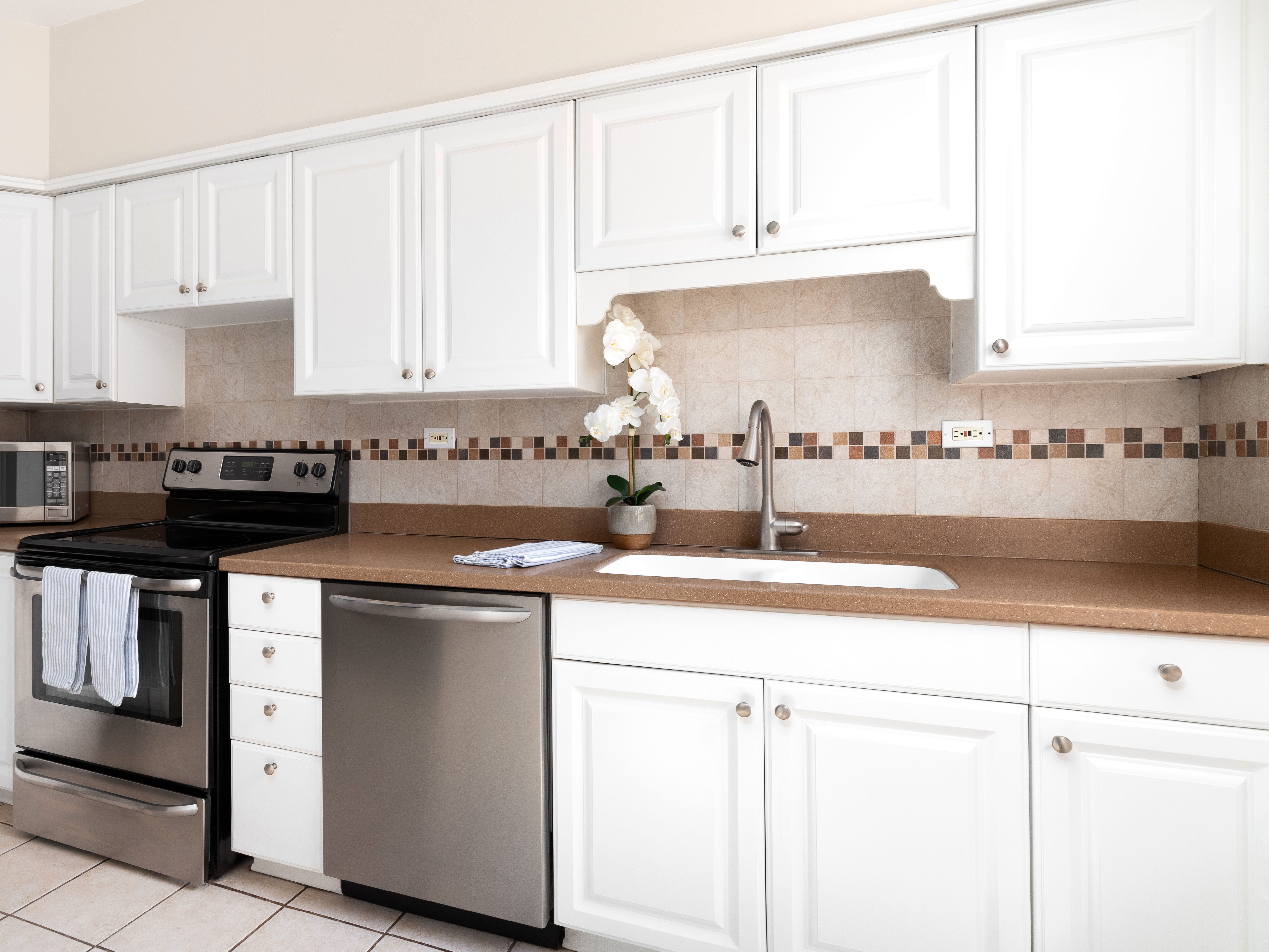 A kitchen with white cabinets and simple silver hardware.