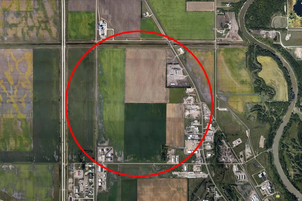 Aerial view of farmland with a red circle highlighting a proposed factory site.