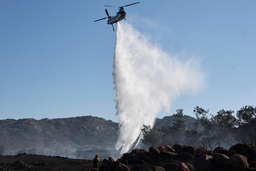 Helicopter dropping water on a wildfire.