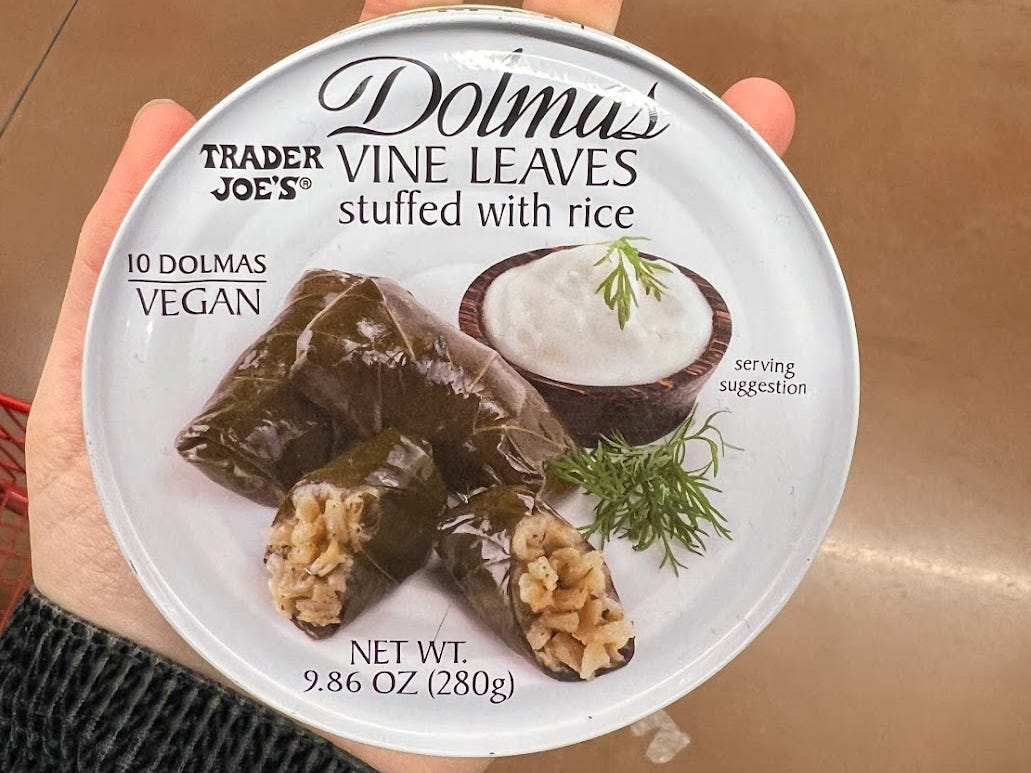 The writer holds up a pack of dolmas with a picture of rice-stuffed vine leaves on the front