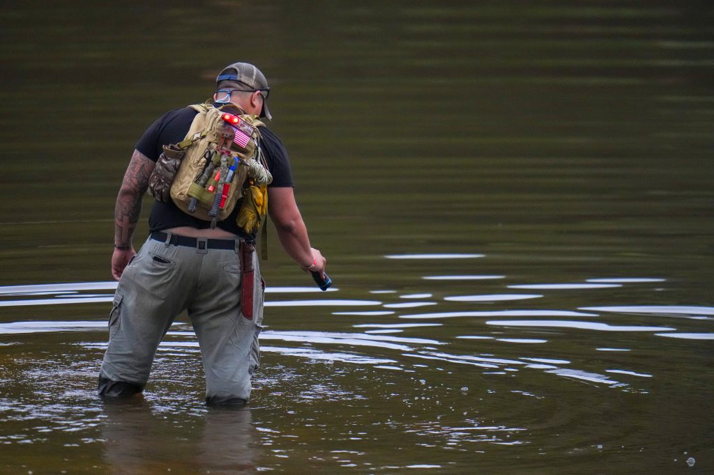 Avi Santos, 23, a civilian from San Antonio, Texas, wades the water  at the Guadalupe River as he helps in the recovery effort