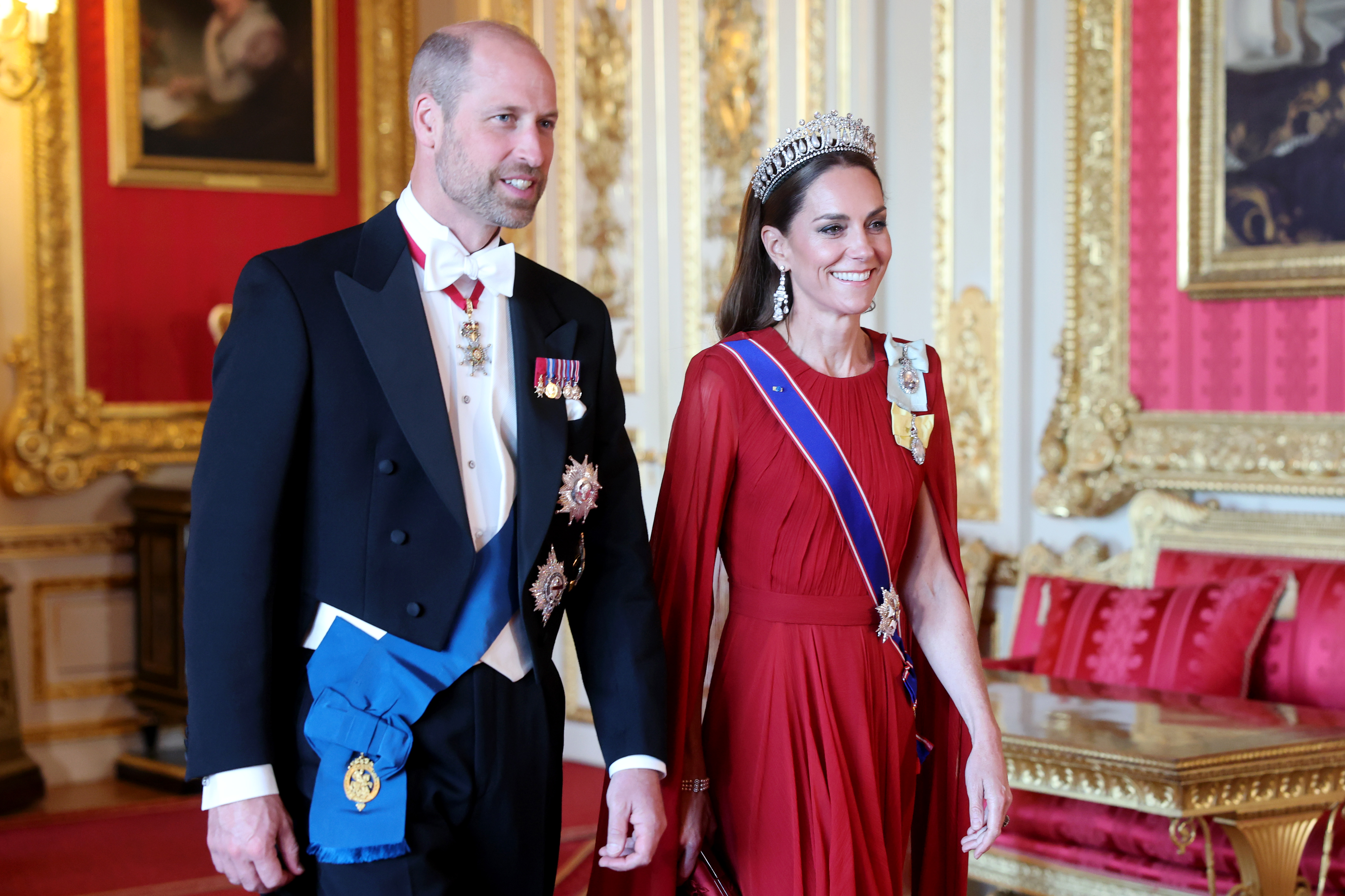 Kate Middleton in a red gown with Prince William in a tuxedo. 