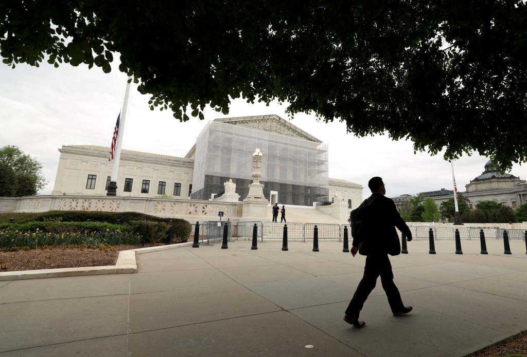 Person walking past the U.S. Supreme Court building, which is under construction.