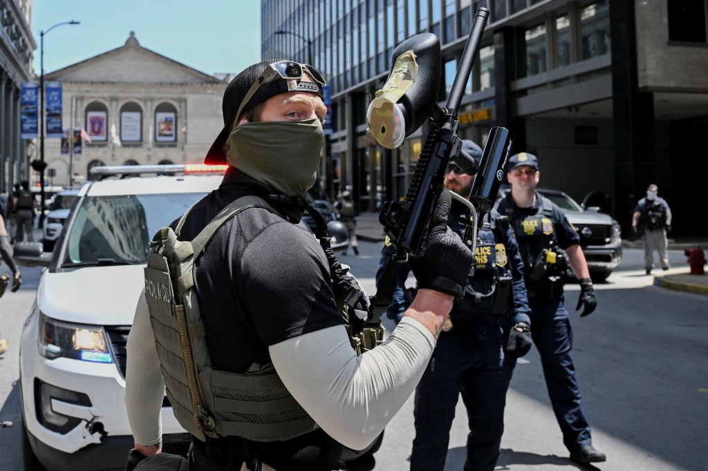 Federal police officers armed with paint ball guns attempt to disperse protesters blocking ICE from raids in Chicago.