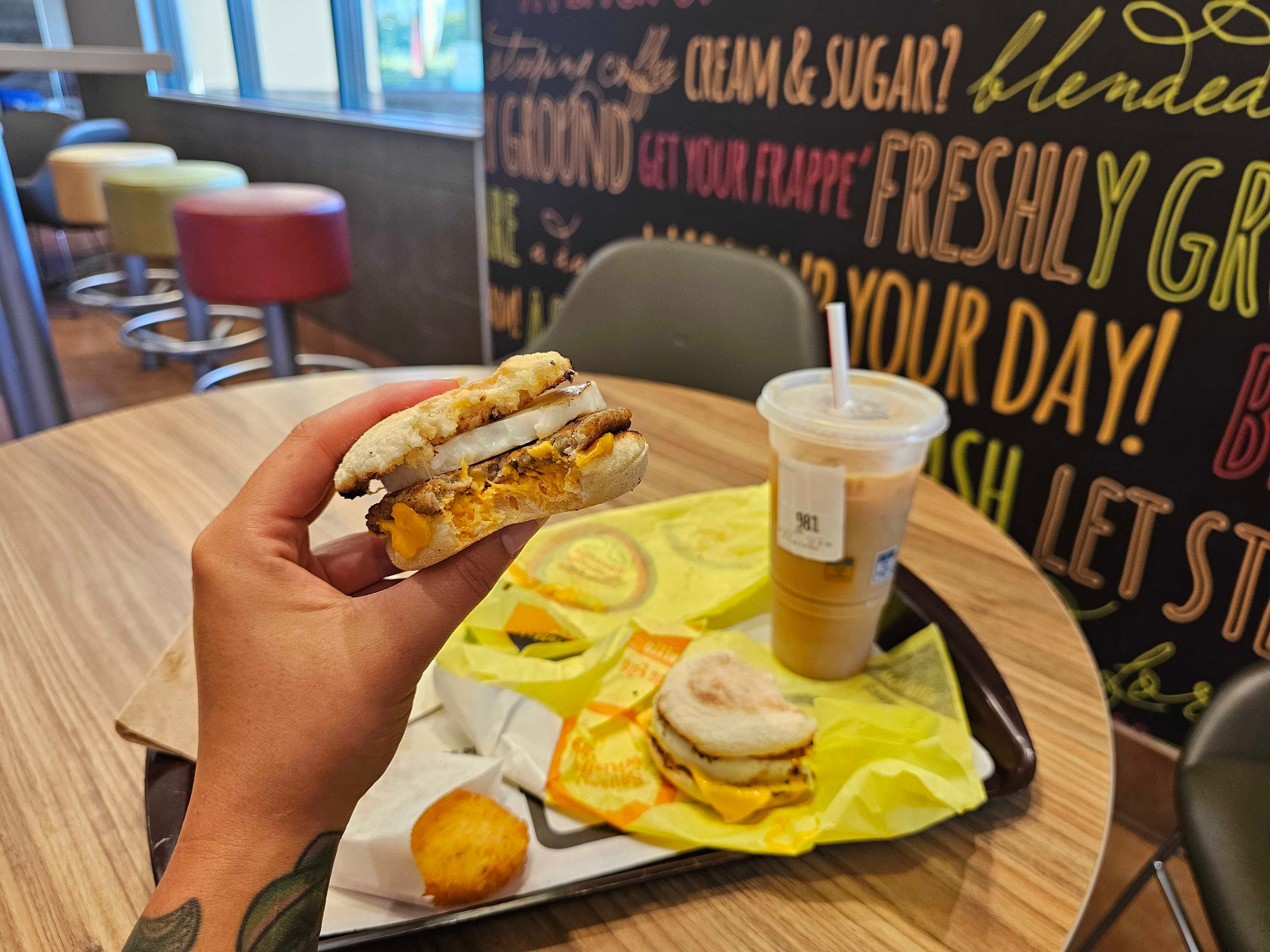 The author holds a McMuffin breakfast sandwich with a bite taken out of it at McDonald's.