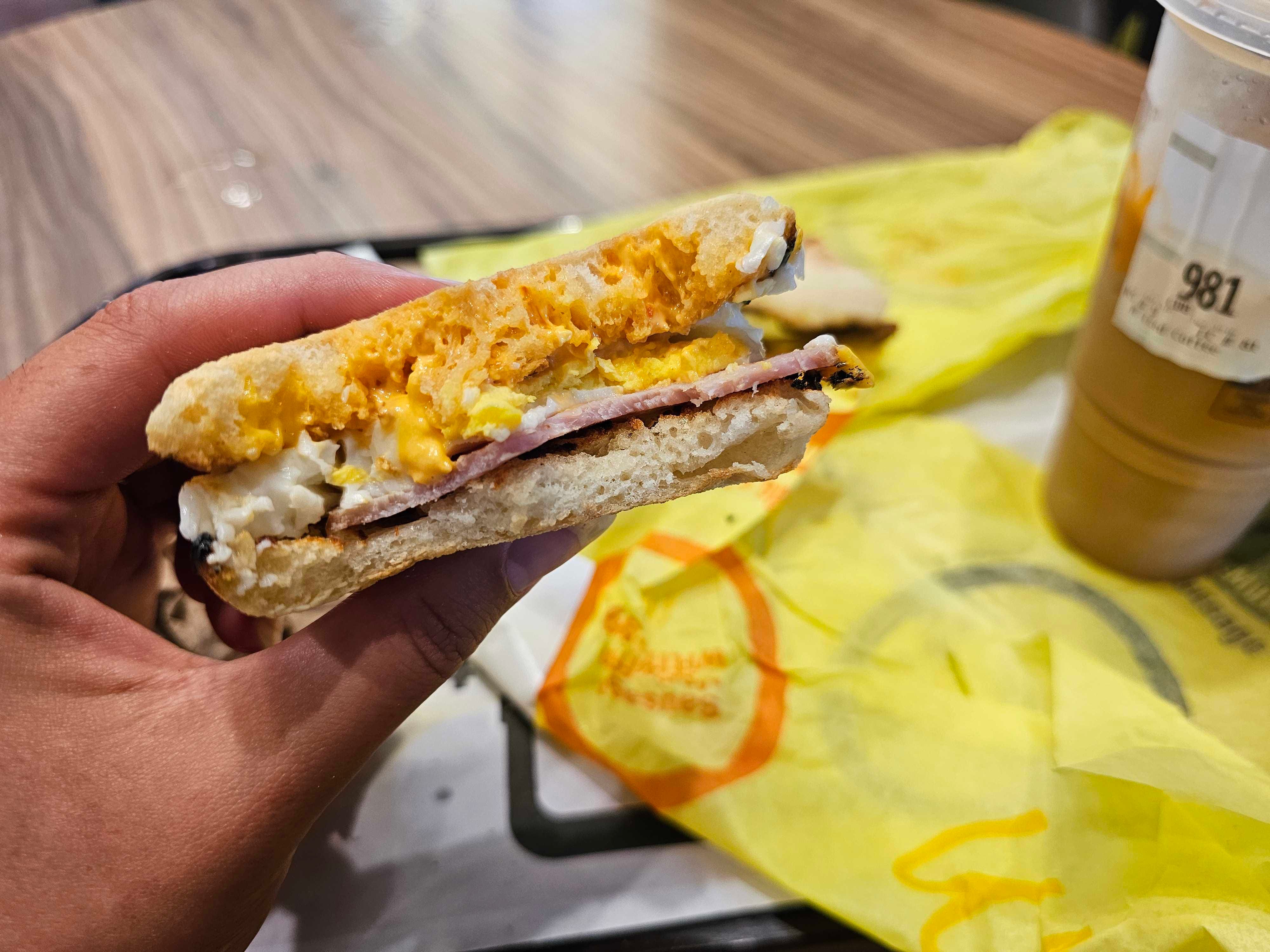 The author holds up a McDonald's McMuffin breakfast sandwich with a bite taken out of it.
