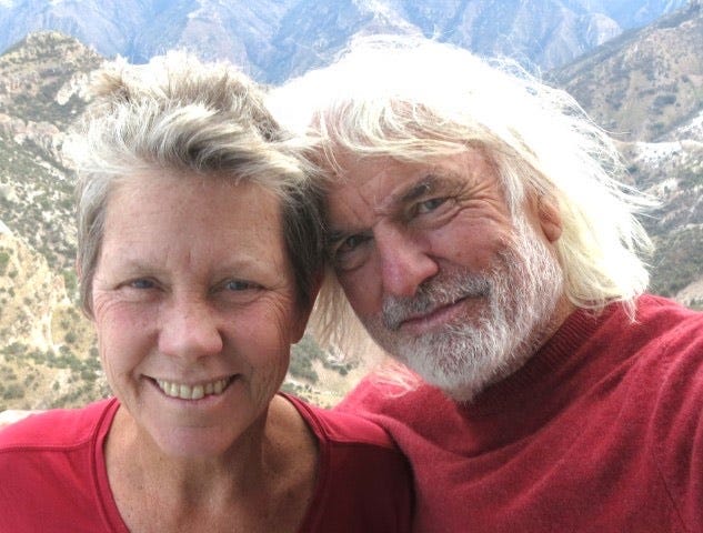 The author and her husband smiling with a mountain view behind them.