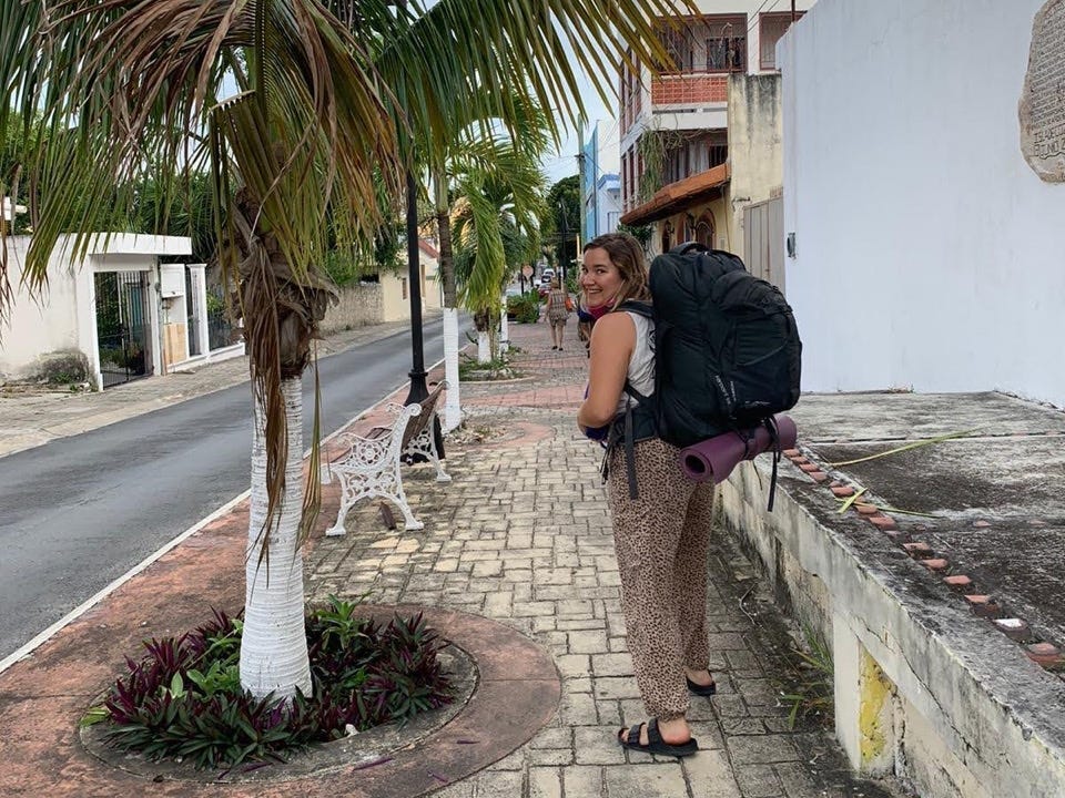 Author Katie Lemon with backpack next to palm tree on cobblestone street
