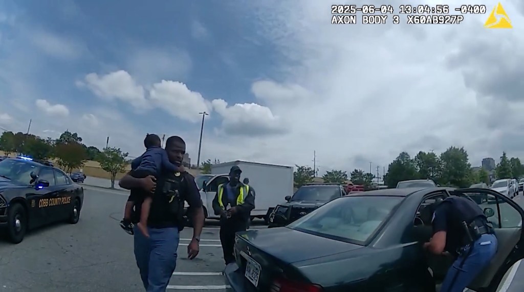 Police officers rescuing two young children from a hot car in a parking lot.