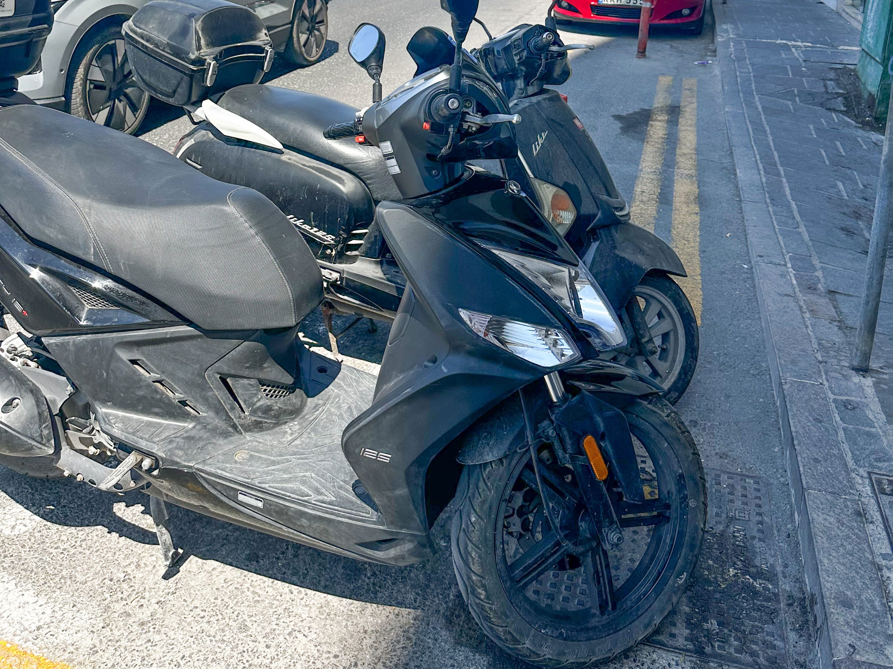 Two mopeds parked on the side of the road.