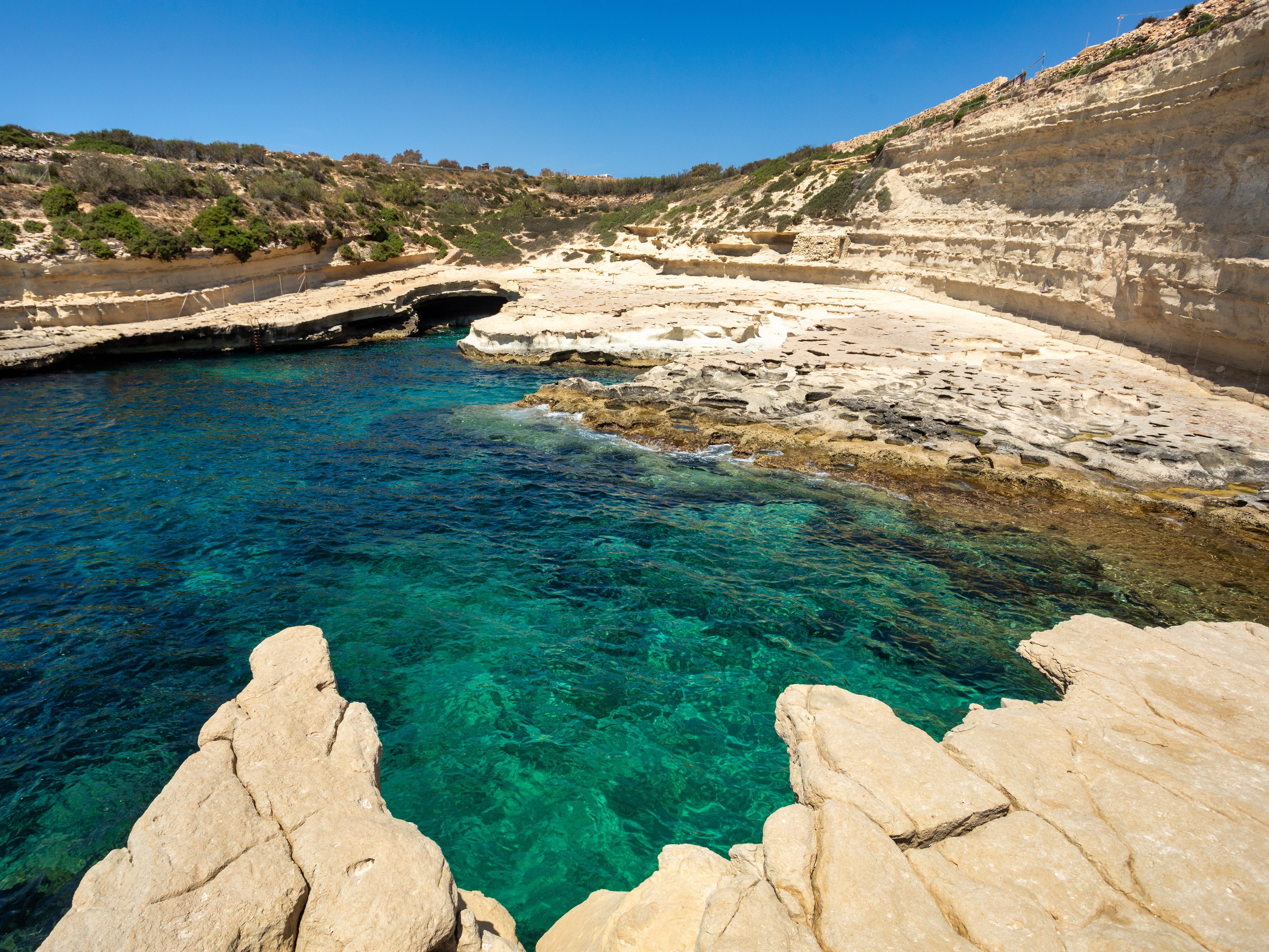Turquoise waters surrounded by rock formations and a rocky shore.