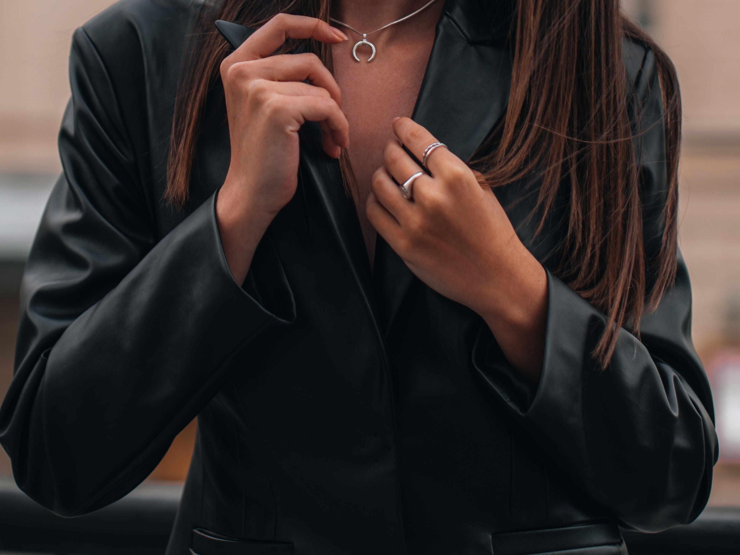 close up of a woman wearing a leather jacket and simple silver jewelry
