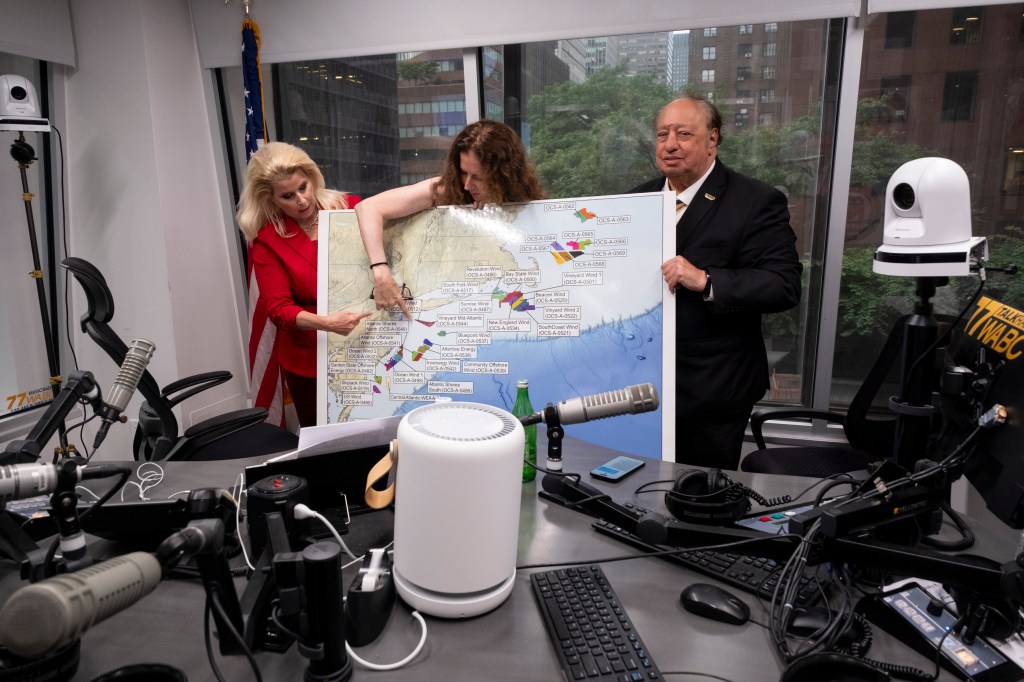 Three people looking at a map of Long Island wind farms.