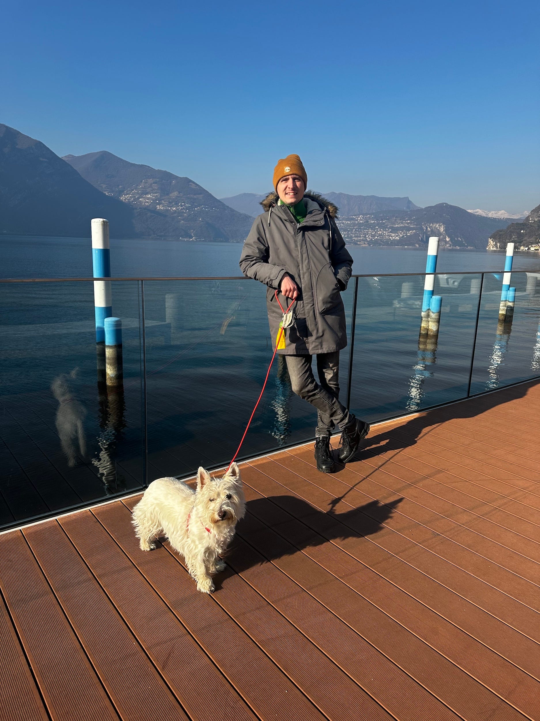A man standing on a pier with a dog.
