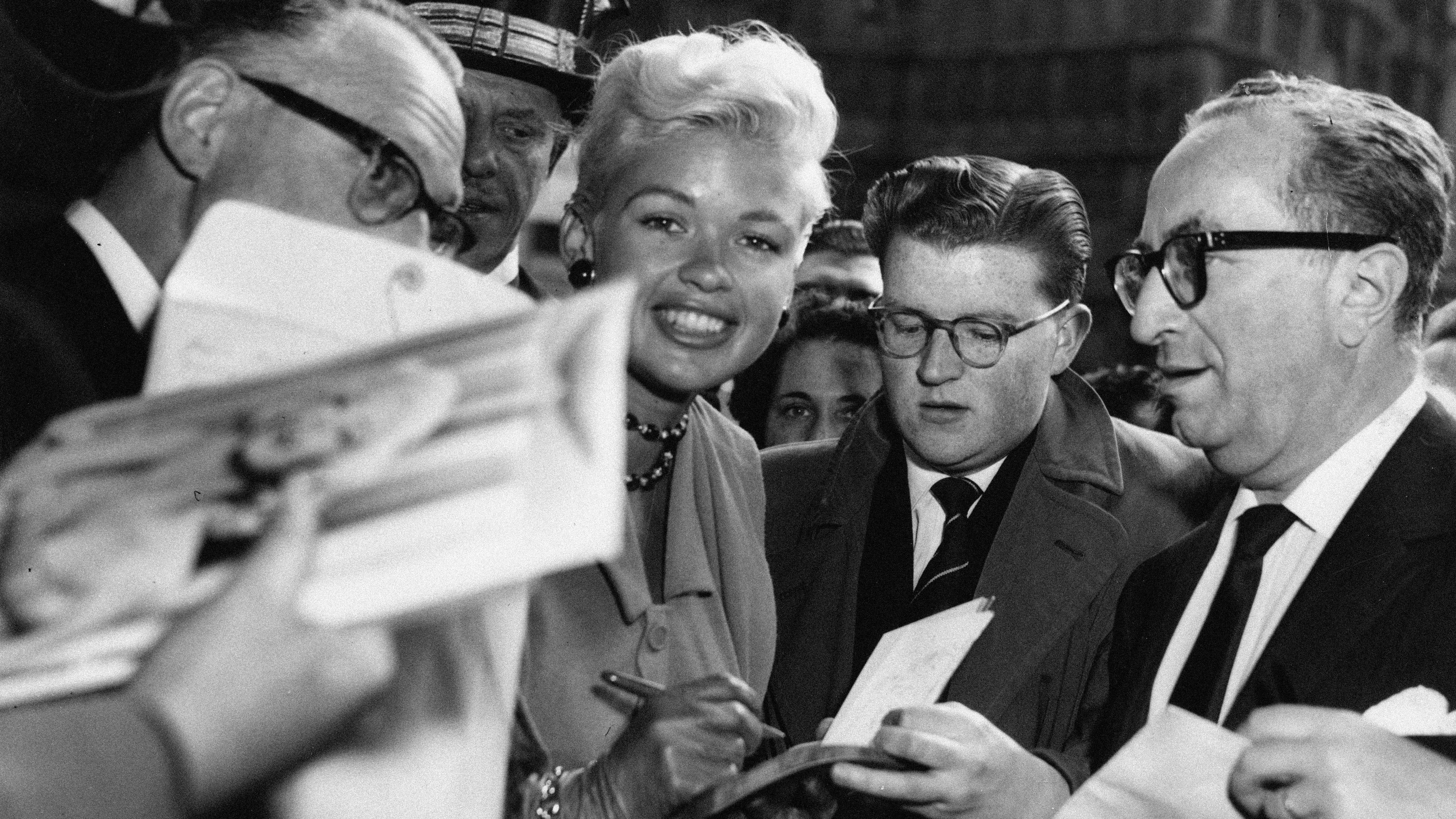 Jayne Mansfield smiles while signing autographs