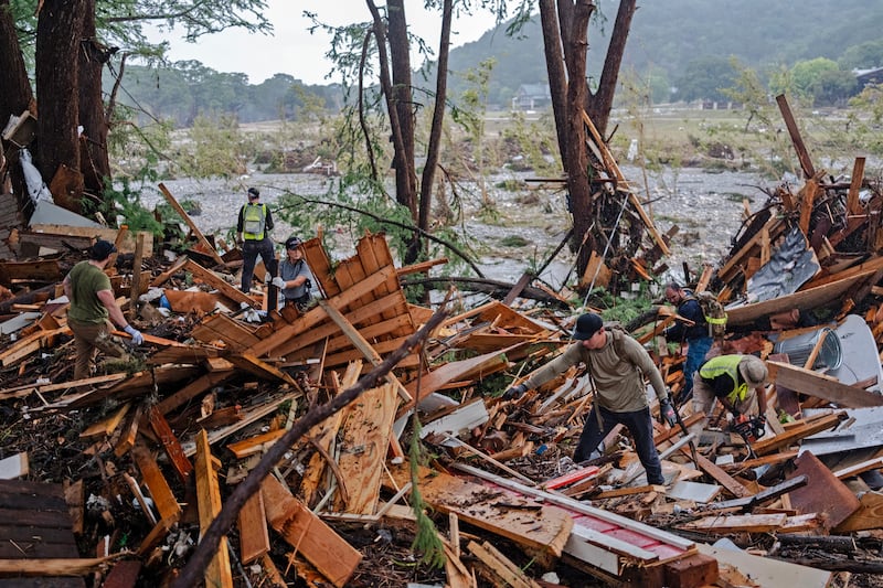 Search and rescue workers dig through debris looking for survivors or remains of people swept up in the flash flooding on July 6, 2025 in Hunt, Texas.