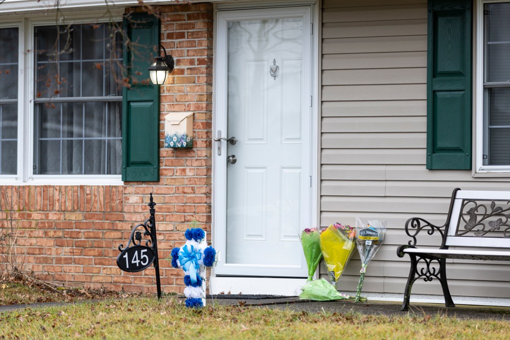Flowers and a cross placed outside a house.