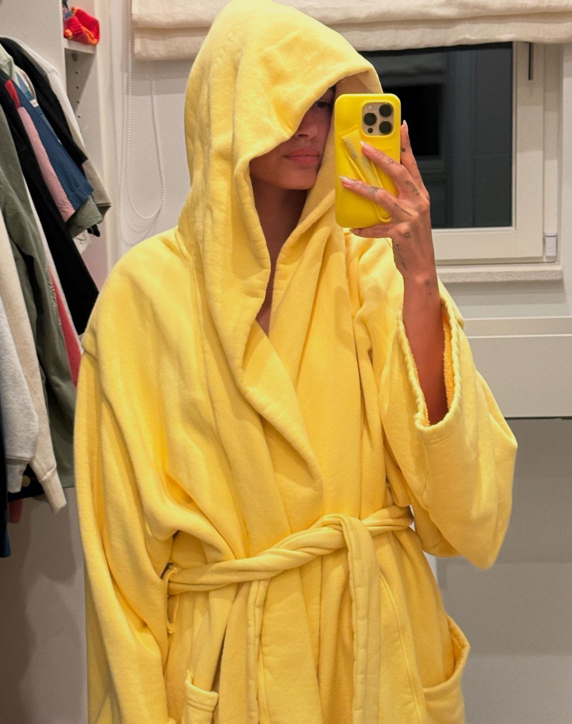 Hailey Bieber wears a yellow robe in a mirror selfie. 
