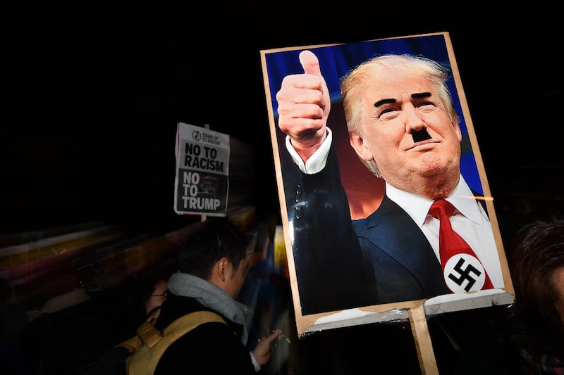 A demonstrator holds a placard showing a picture of US President-elect Donald Trump modified to add a swastika and an Adolf Hitler-style moustache during a protest outside the US Embassy in London November 9, 2016 against Trump after he was declared the winner of the US presidential election.