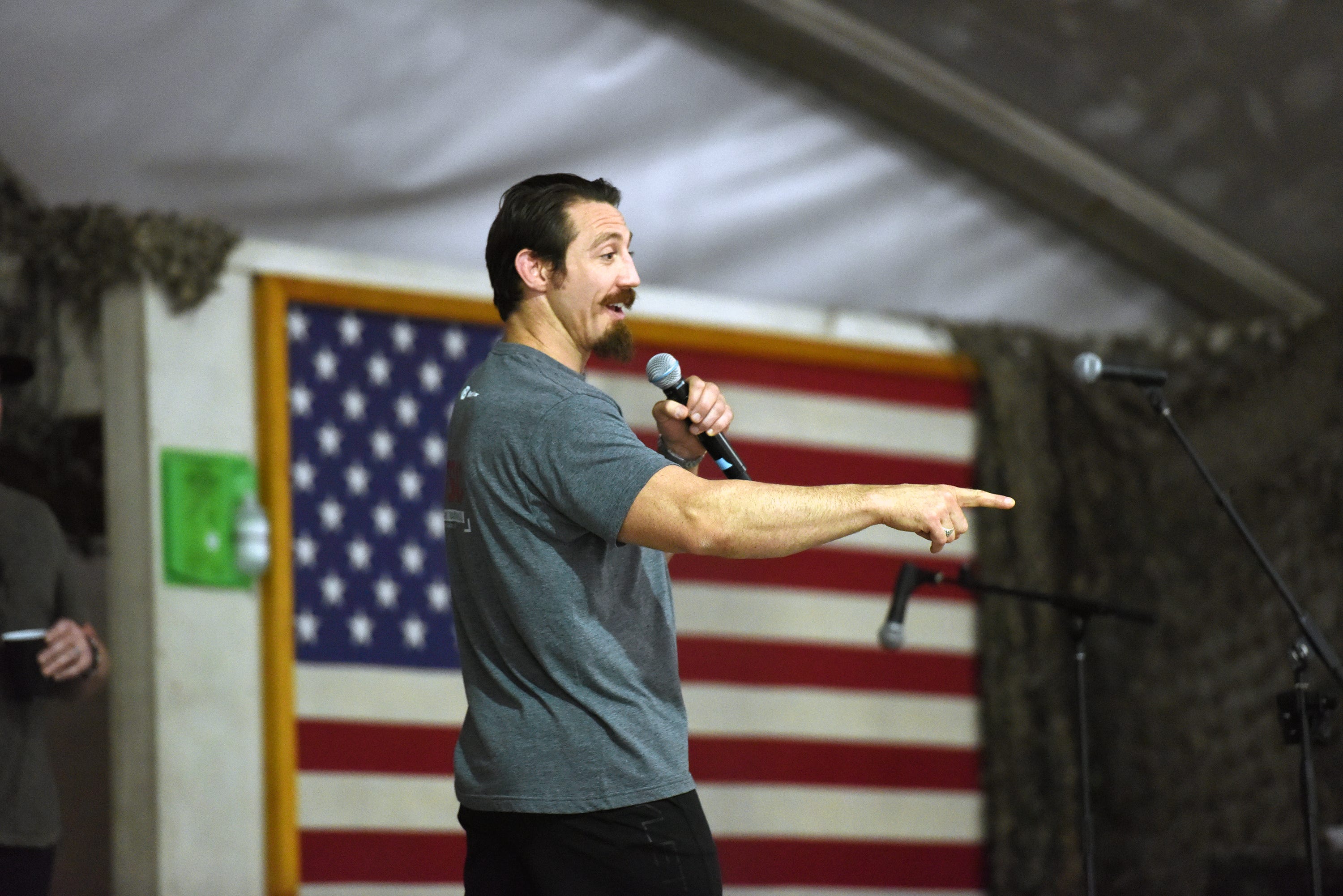 Tim Kennedy speaking into a microphone in front of an American flag