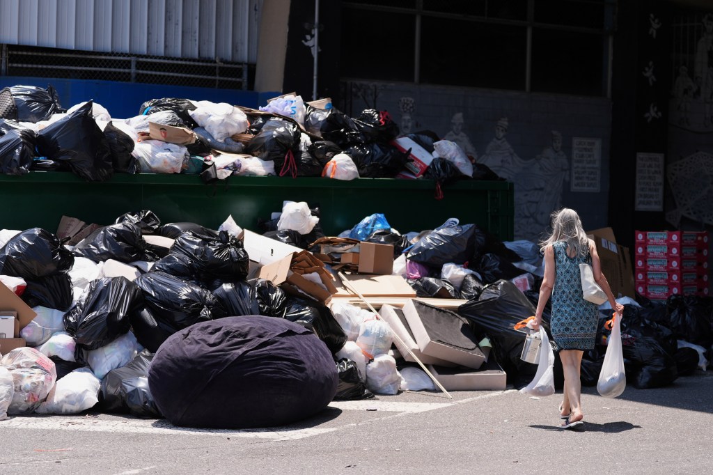 A woman drops off trash at a garbage collection site on July 3, 2025.
