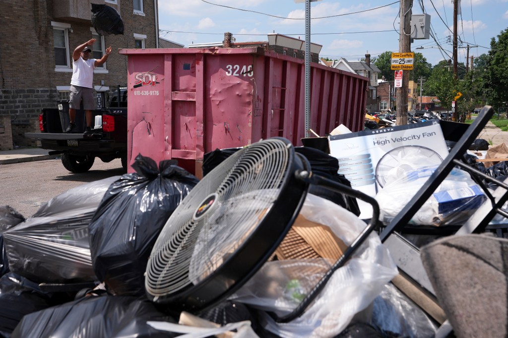A man throws a bag of garbage into a bin as trash piles up on the streets of Philadelphia during the strike.
