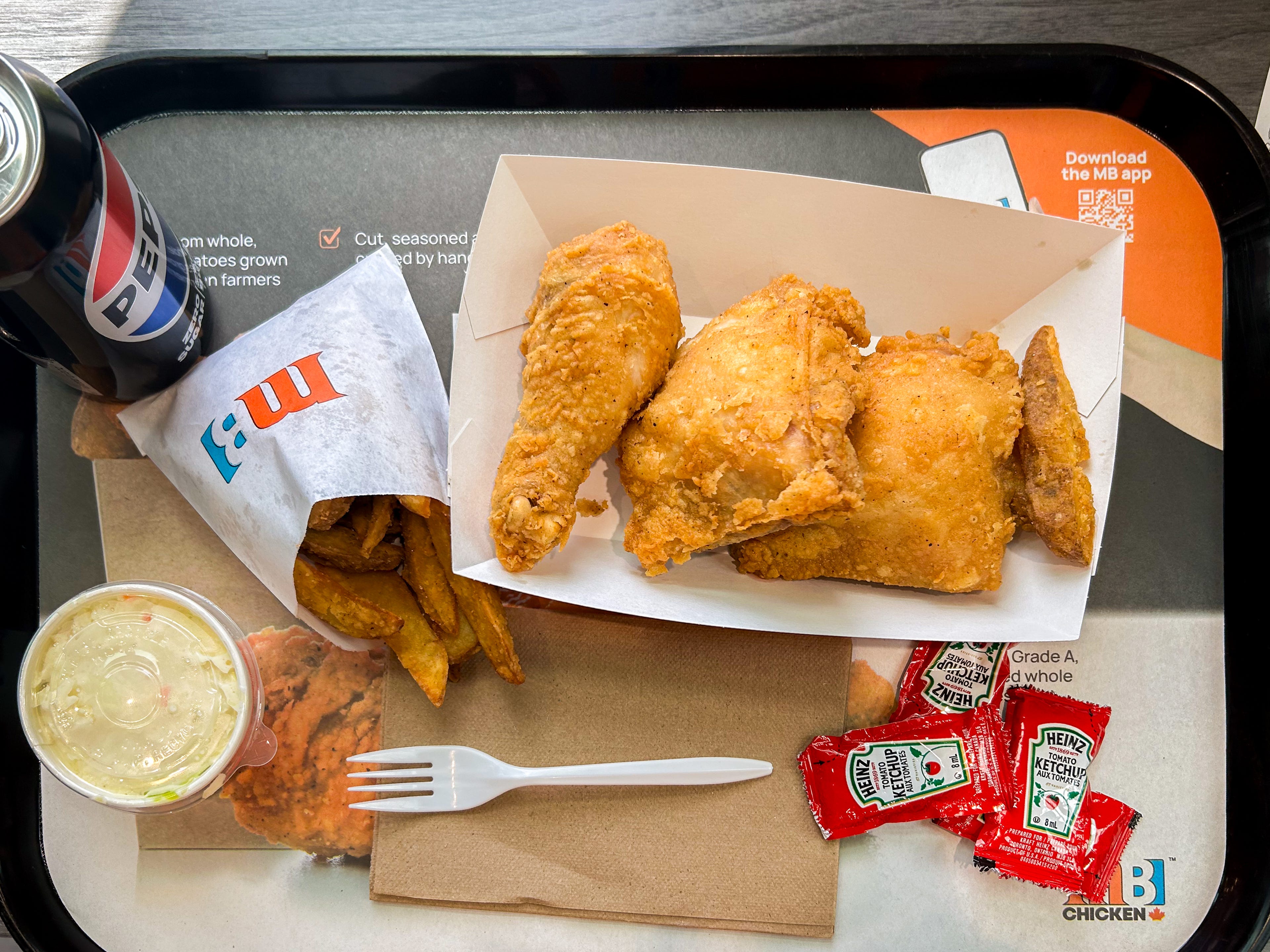 An aerial shot of a Mary Browns chicken tray with for bone-in pieces of chicken, fries, coleslaw and a Pepsi Zero