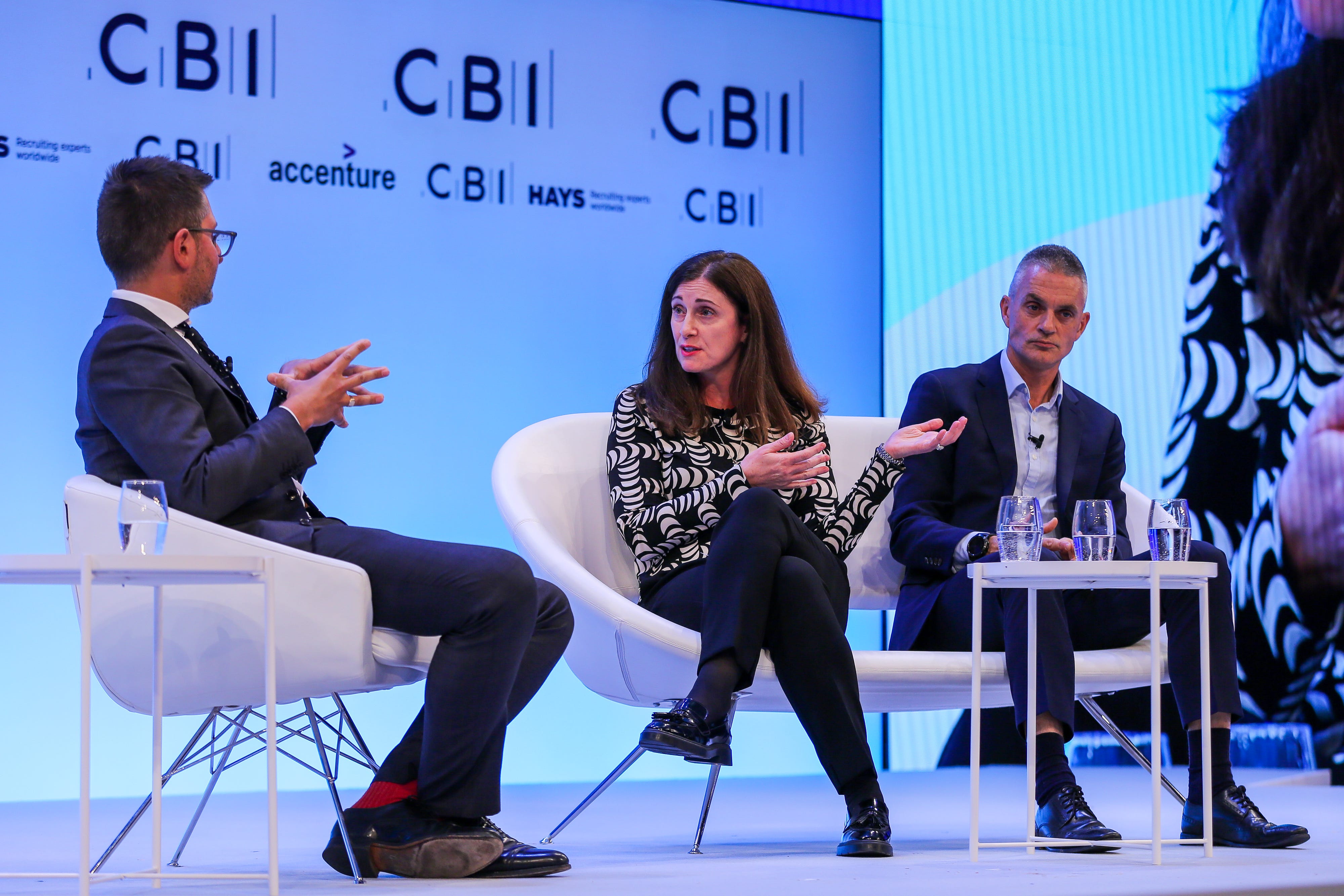 A photo of a two men and a woman seated on stage